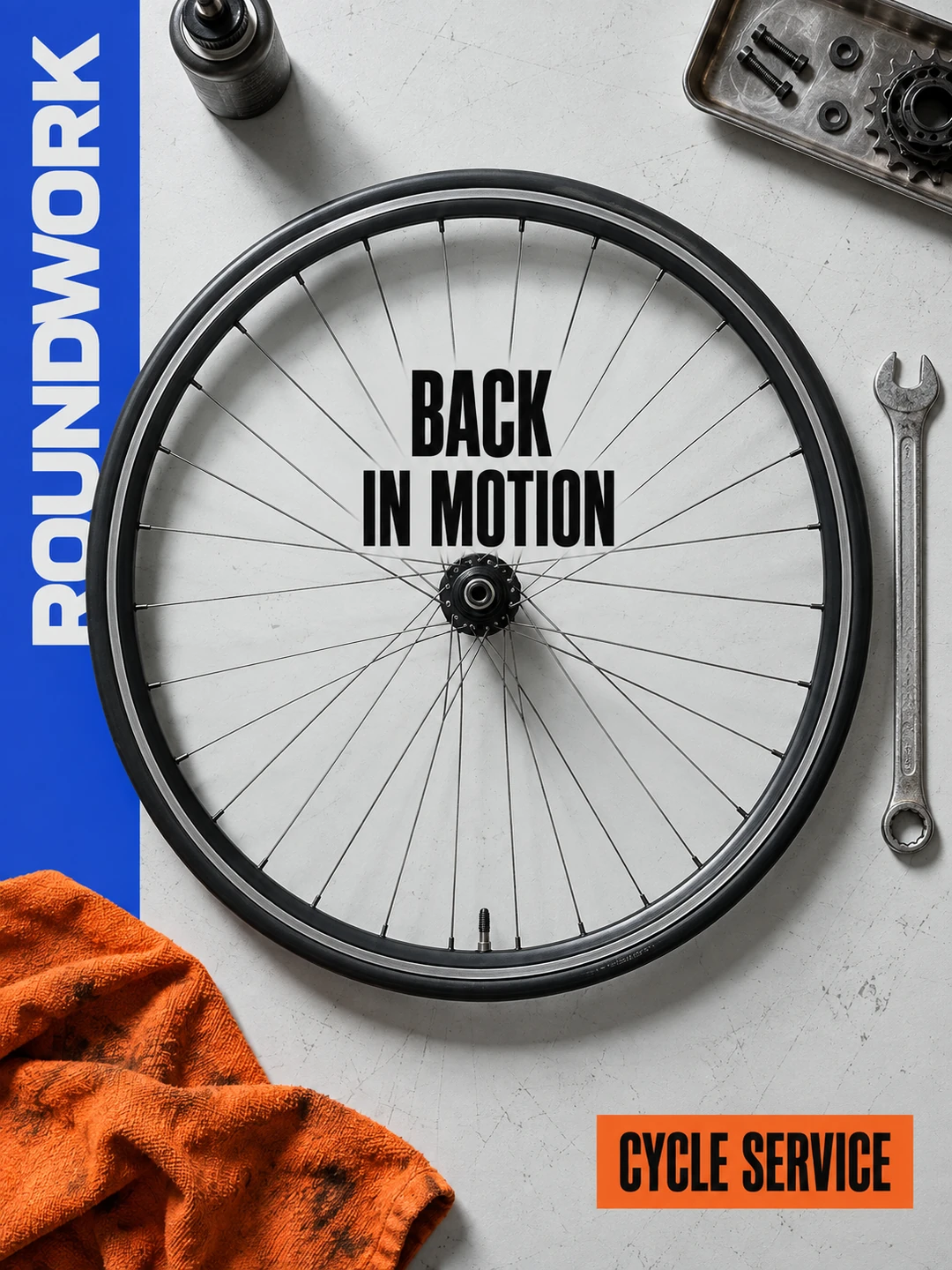 A single complete bicycle front wheel lies on a light grey workbench. Every spoke correctly connects rim and hub. A wrench rests vertically to the right outside the wheel, an orange workshop…