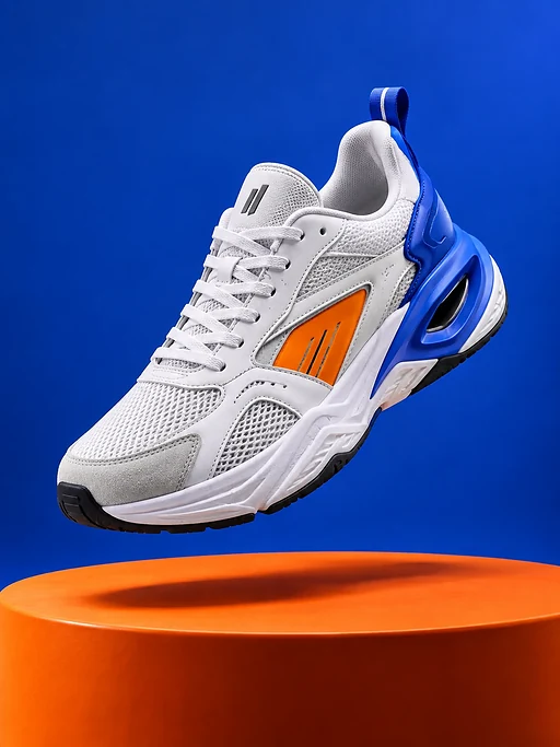 Ein weißer Sneaker mit blauer Ferse und orangefarbenem Detail schwebt über einem orangefarbenen Podest vor kobaltblauem Hintergrund.